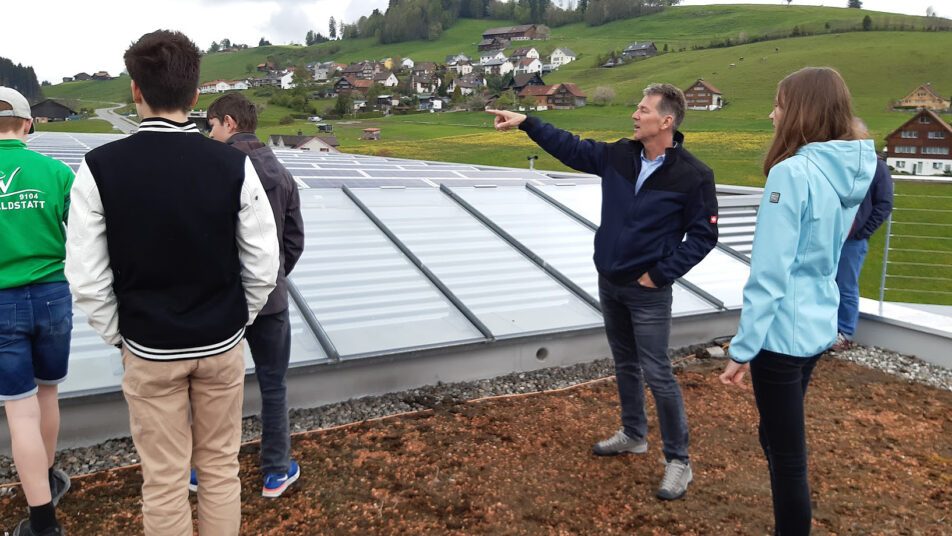 Thomas Holerdegger, Mitinhaber der Blumer Techno Fenster AG, besichtigte mit den Jugendlichen die Fotovoltaikanlage auf dem Firmendach. 