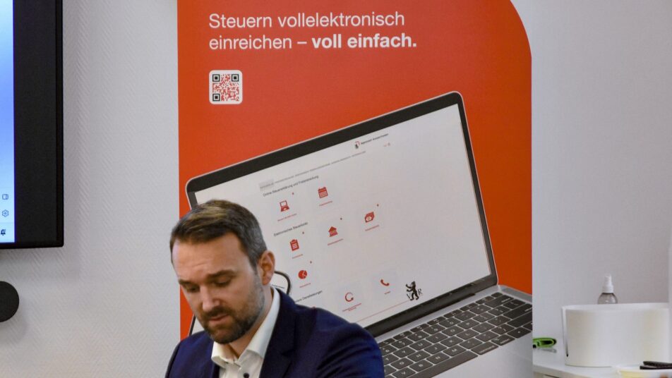 Roman Scherrer von der Kantonalen Steuerverwaltung vor dem Plakat zur elektronischen Steuereinreichung.