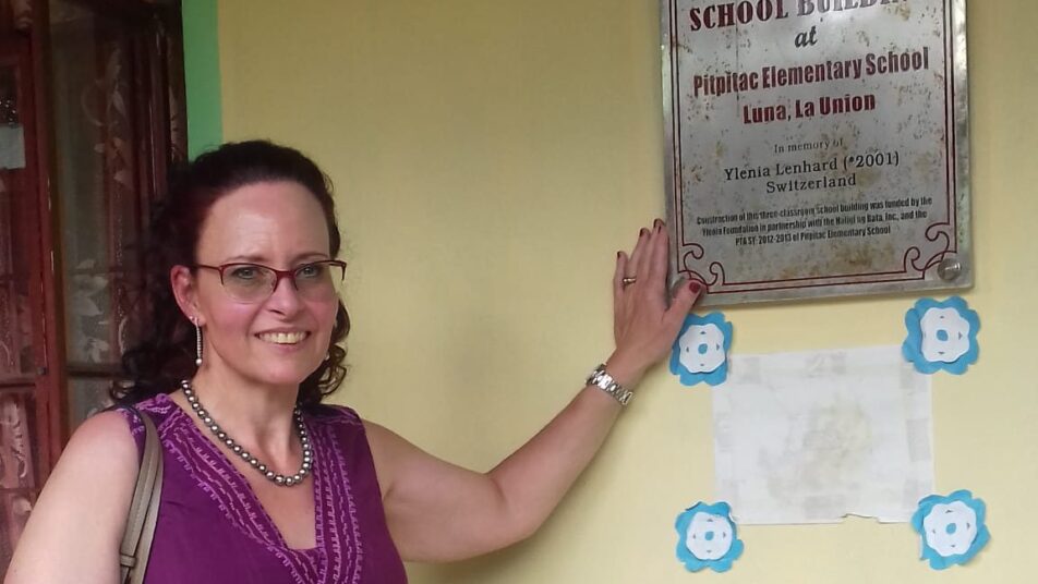 Charlotte Lenhard bei ihrem ersten Besuch auf den Philippinen: Am Schulgebäude hängt ein Schild, das die Unterstützung der Stiftung YLENIA zeigt. (Bild: zVg)